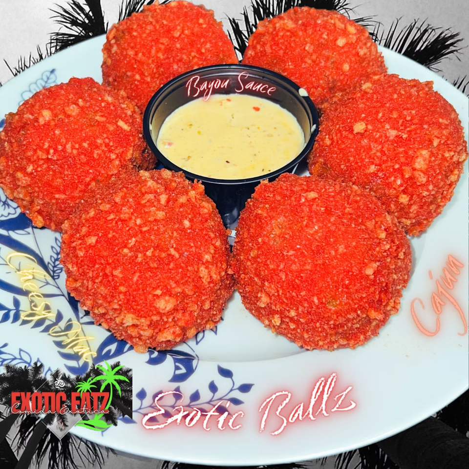 Six red, breaded Exotik Ballz on a plate with a side of Bayou Sauce.